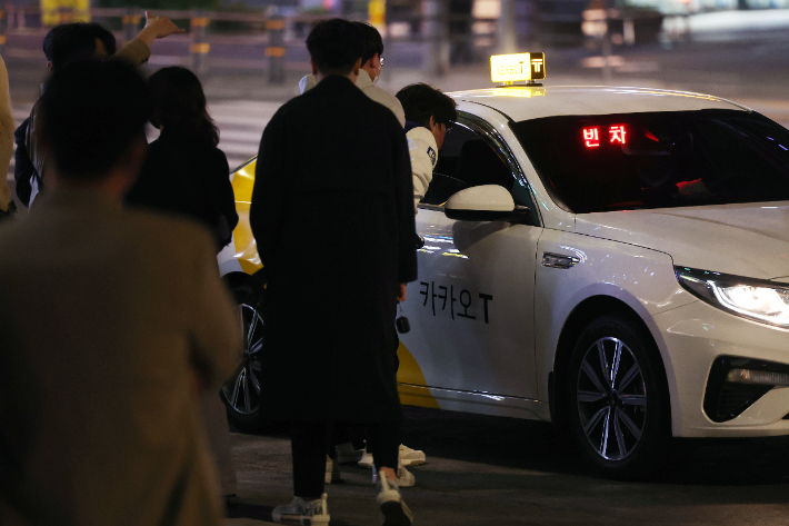 코로나19 방역을 위한 사회적 거리두기가 전면 해제된 18일 자정을 넘긴 시간 서울 강남역 인근에서 시민들이 빈 택시를 향해 모여들고 있다. 연합뉴스
