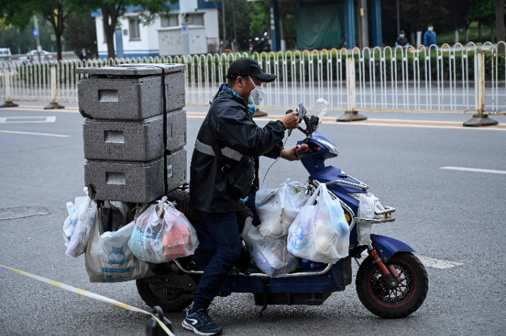 코로나19 확산세가 이어지는 중국 수도 베이징의 거리에서 10일 한 슈퍼마켓 배달원이 스쿠터를 타고 물품 배달에 나서고 있다. 연합뉴스