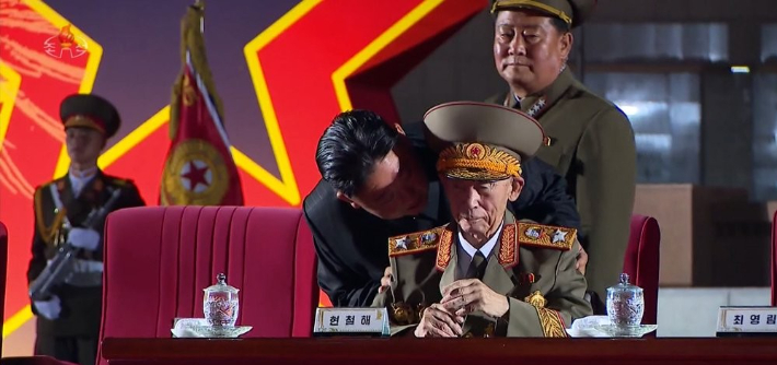 김정은 북한 국무위원장이 참전 경험이 있는 원로 간부 현철해의 뒤에서 몸을 숙여 들여다보며 어깨를 감싸고 있다. 연합뉴스