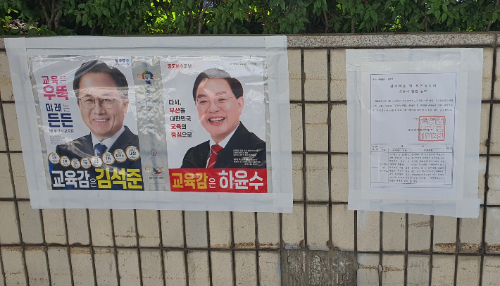 두 후보의 선거 벽보 옆에 하윤수 후보의 학력을 바로 잡는 선관위의 공고문이 붙어있다/김석준 캠프 제공