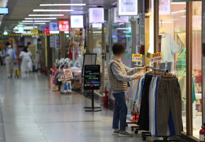 지난 29일 서울 명동 인근 지하상가 한 옷 가게에서 상인이 옷을 진열하고 있다. 연합뉴스