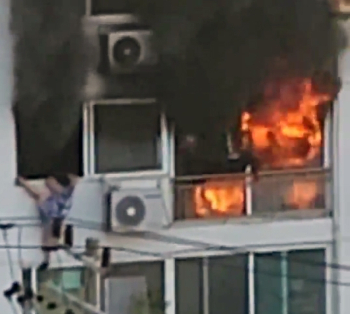 3일 오전 6시 35분쯤 전남 광양시 광영동 한 아파트 6층에서 불이 나 대피한 주민이 베란다에 매달려 있다. 연합뉴스