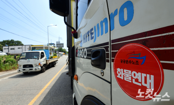 민주노총 공공운수노조 화물연대가 총파업 이틀째인 8일 오전 경기 이천시 하이트진로 이천공장에서 주류를 실은 화물 트럭이 운행 중단된 화물연대 트럭 옆을 지나고 있다. 이천=황진환 기자