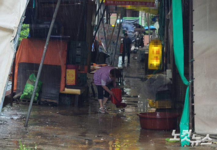 9일 인천 미추홀구 제일시장 내 한 상인이 폭우에 잠긴 시장 바닥을 양동이로 퍼내는 모습. 주영민 기자