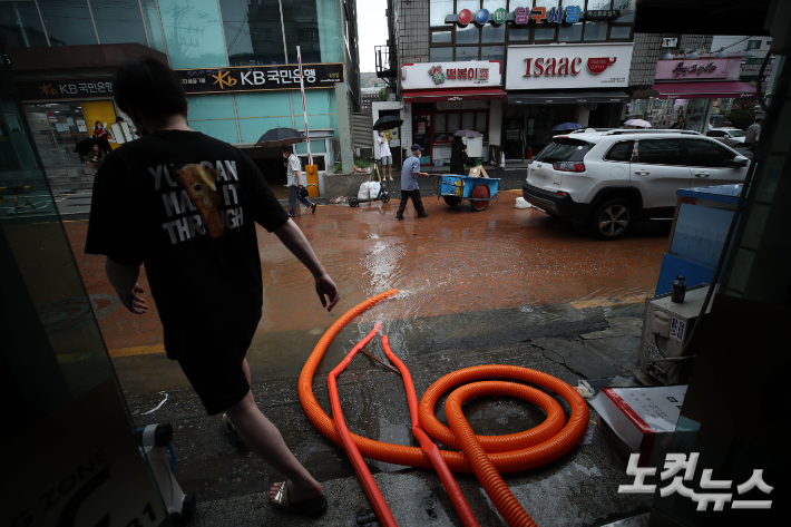 9일 오전 서울 동작구 성대전통시장에서 시민들이 전날 내린 폭우로 침수된 매장의 물을 빼내고 있다. 황진환 기자