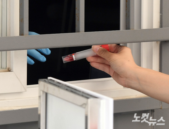 코로나19 임시선별검사소에서 한 시민이 검사키트를 의료진에게 제출하고 있다. 황진환 기자