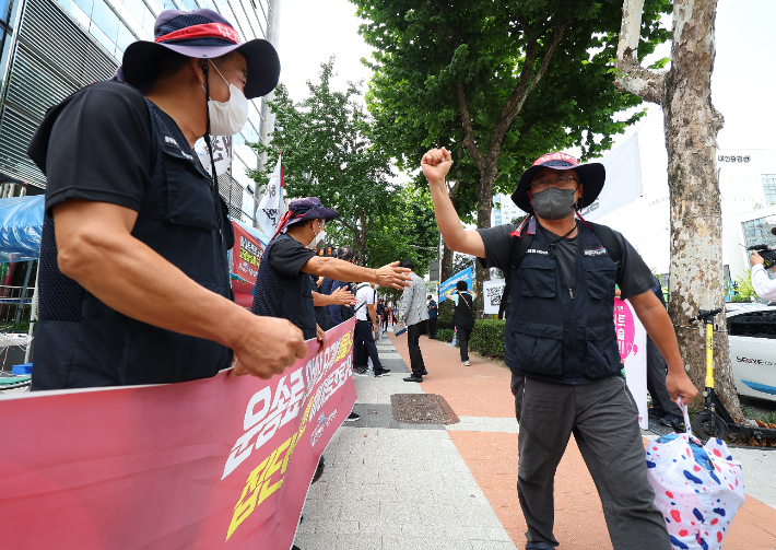 24일 오전 하이트진로 본사 로비 점거를 해제한 공공운수노조 화물연대 조합원이 서울 강남구 본사 건물을 나와 다른 조합원들의 격려를 받고 있다. 연합뉴스