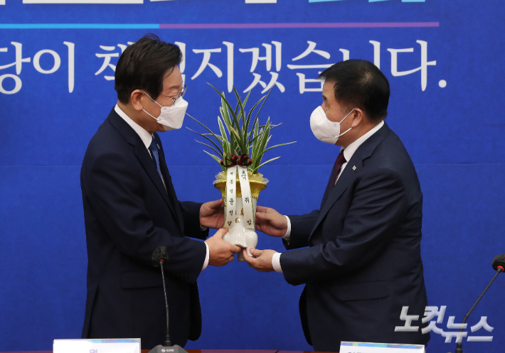 이재명 더불어민주당 신임 대표가 30일 서울 여의도 국회에서 이진복 대통령실 정무수석으로부터 윤석열 대통령의 축하난을 전달받고 있다. 윤창원 기자