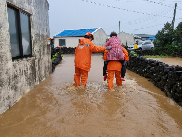 4일 서귀포시 대정읍 영락리에서 갑자기 쏟아진 폭우에 주택과 도로가 침수돼 119가 한 할머니를 구조하고 있다. 제주도소방안전본부 제공