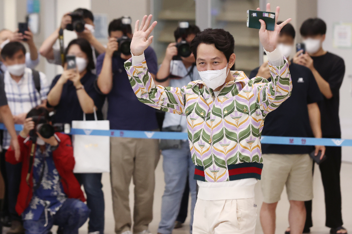 이정재가 인천국제공항에 나와 있는 팬들에게 손을 들어 인사하고 있다. 연합뉴스