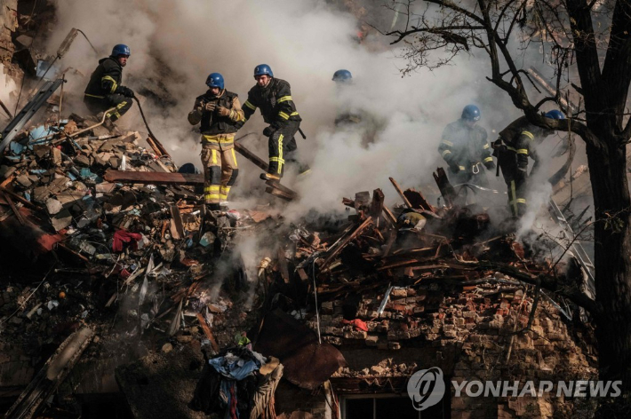 (키이우 AFP=연합뉴스) 17일 우크라이나 수도 키이우 시내에서 소방관들이 자폭 무인기를 이용한 러시아군의 공격으로 발생한 화재를 진압하고 있다. 2022.10.17 연합뉴스