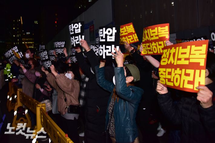 더불어민주당 의원들이 지난 19일 서울 여의도 중앙당사 앞에서 민주연구원 압수수색에 나선 검찰 관계자들과 대치하고 있는 가운데 당사 앞으로 모인 지지자들이 '야당탄압 중단' 구호를 외치고 있다. 윤창원 기자