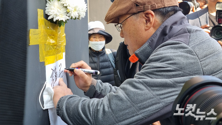 30일 오후 1시 30분쯤 강모씨가 '근조' 글씨를 적으며 희생자를 추모하고 있다. 양형욱 기자.