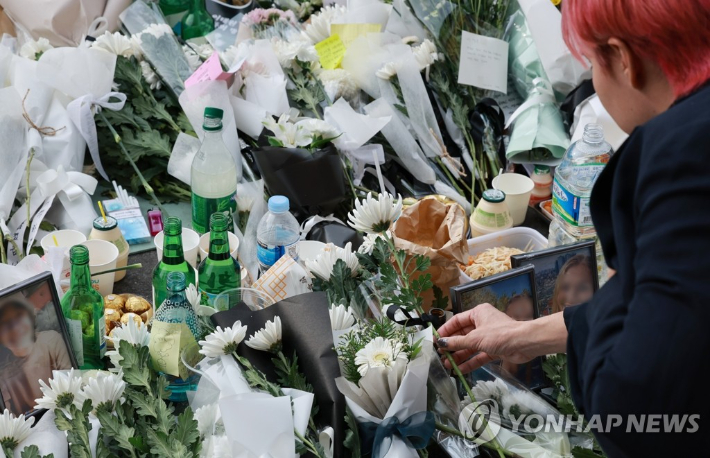 1일 서울 용산구 이태원역 1번 출구 앞에 마련된 추모 공간에서 한 시민이 국화꽃을 놓고 있다. 연합뉴스