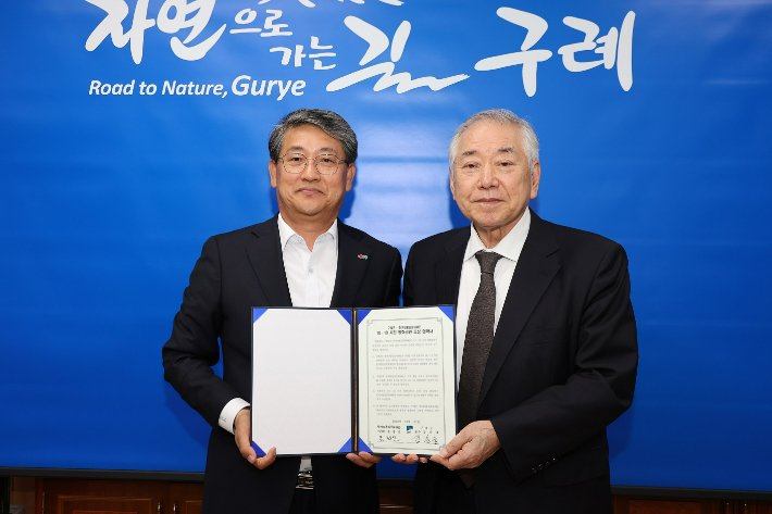 김순호 구례군수(왼쪽)와 문정인 이사장이 여순평화공원 조성 협약서를 함께 들고 있다. 구례군 제공