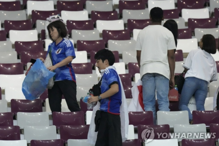 경기 후 파란색 비닐봉지에 쓰레기를 담는 일본 팬들. 연합뉴스