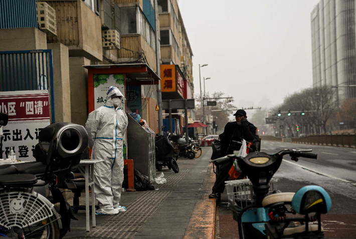 최근 코로나19 감염자 급증으로 중국 베이징에서 봉쇄조치가 시행되는 가운데 한 보건당국 직원이 24일(현지시간) 봉쇄된 한 주택지구 입구를 지키고 있다. 연합뉴스