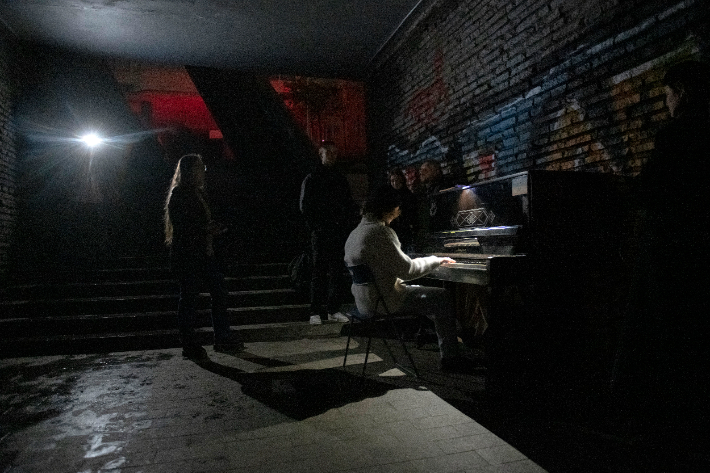 전쟁으로 전기가 끊겨 어두운 공간에서 한 키이우 시민이 피아노를 치고 있다. 연합뉴스