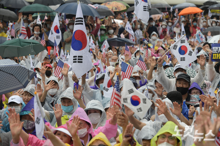 서울 종로구 동화면세점 앞에서 열린 광복절 집회에서 참석자들이 태극기와 성조기를 흔들고 있다. 이한형 기자