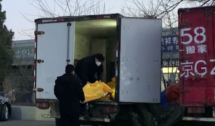 Trabalhadores carregam corpos de funerária em Pequim.  Yonhap News