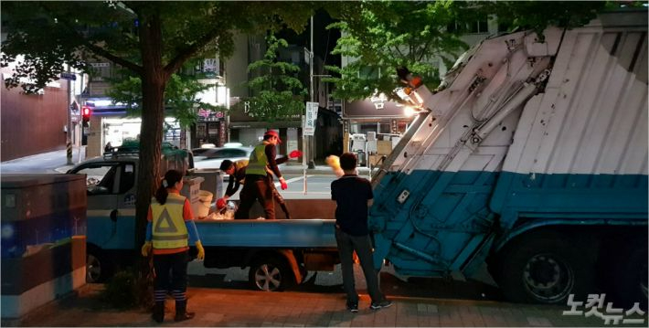  부산의 한 도로에서 미화원들이 소형 화물차에 올라 대형 수거차에 쓰레기를 옮겨 담는 작업을 하고 있다. 사진은 기사 내용과 직접적인 연관 없음. 박진홍 기자