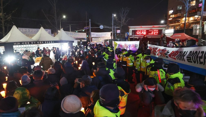 지난달 25일 서울 용산구 녹사평역 광장에 마련된 이태원참사 희생자 시민분향소에서 천주교 정의구현전국사제단 소속 신부들이 참사 희생자와 유가족을 위한 성탄대축일 미사를 집전하는 가운데(왼쪽) 보수 단체가 집회를 하고 있다. 연합뉴스