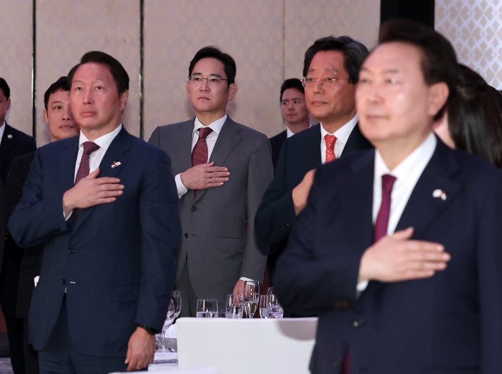 윤석열 대통령이 16일 오후(현지시간) 콘래드 아부다비 에티하드타워에서 열린 동행 경제인과의 만찬 간담회에서 국기에 경례하고 있다. 이날 행사에는 이재용 삼성전자 회장(왼쪽 두번째)과 최태원 대한상공회의소회장(왼쪽) 등이 함께 했다. 연합뉴스