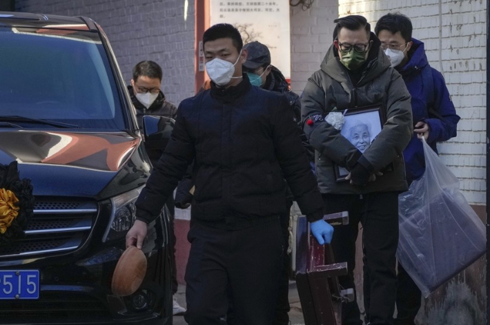 지난해 12월 19일 중국 베이징의 한 발열 진료소 밖에서 영정 사진을 든 유족들이 시신을 운반하는 영구차 옆을 지나가고 있다. 연합뉴스