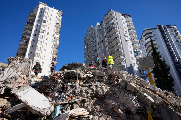 튀르키예 지진으로 인해 붕괴된 건물 잔해에서 응급팀이 사람들을 찾고 있는 가운데 일부 건물은 멀쩡히 서 있는 것이 보인다. 연합뉴스