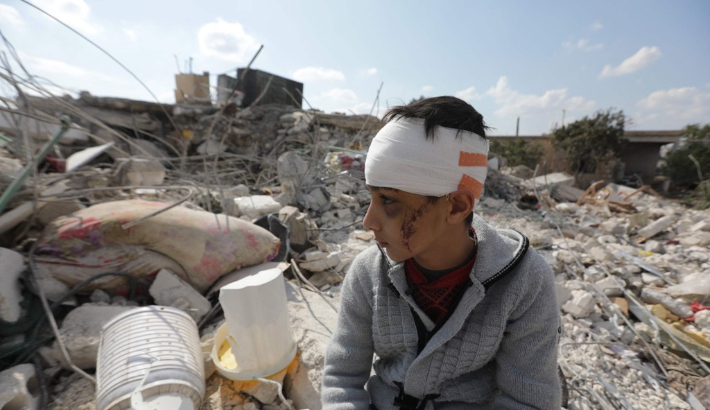 11일(현지 시각) 시리아 알레포주 진데리스에서 한 소년이 머리에 붕대를 감은 채 지진으로 붕괴한 건물 잔해 더미에 앉아 있다. 이 소년은 시리아와 인접한 튀르키예 남동부에서 지난 6일 발생한 강진으로 가족을 잃었다. 이번 지진으로 지금까지 양국에서 2만8천 명 이상이 사망했다. 연합뉴스