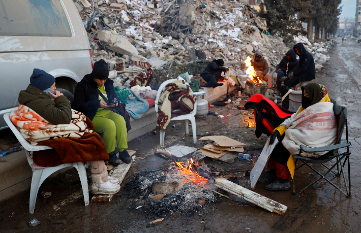 13일(현지시간) 튀르키예 카라만라스에서 지진 피해 생존자들이 불 옆에서 몸을 녹이고 있다. 생존자들은 추위와 배고픔, 전염병 등 2차 재난에 노출된 상황이다. 연합뉴스