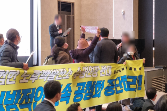 지난해 12월 부산 남구에서 열린 고리2호기 계속 운전 관련 방사선환경영향평가서 초안 공청회장에서 환경단체 회원(현수막 주변)들이 반발하는 가운데 한수원 관계자(단상 맨 위)가 공청회를 진행하고 있는 모습. 박진홍 기자