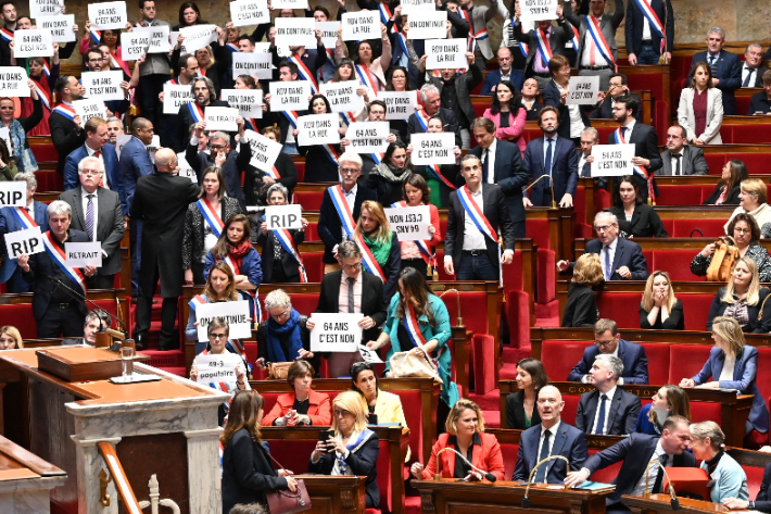 프랑스 하원에서 20일(현지시간) 엘리자베트 보른 총리에 대한 첫번째 불신임안이 부결되자 극좌 성향의 굴복하지않는프랑스(LFI) 의원들이 '64세는 안 된다'고 적힌 종이를 들고 일어나 항의하는 모습. 연합뉴스