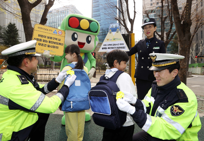 도로교통공단이 28일(화) 진행한 '어린이 교통사고 ZERO 캠페인'에서 경찰관이 어린이 책가방에 보행 안전용품을 매달아주고 있다.  도로교통공단 제공