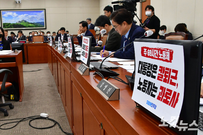 21일 서울 여의도 국회에서 열린 환경노동위원회 전체회의에서 더불어민주당 의원들이 자리에 주69시간노동제 '대통령은 칼퇴근, 노동자는 과로사' 피켓을 붙이고 있다. 윤창원 기자