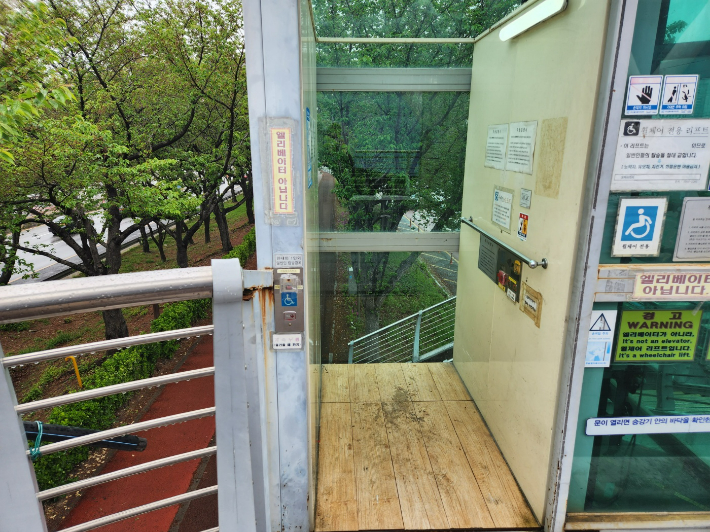 육교에 설치된 휠체어리프트 내부가 협소해 휠체어를 탄 장애인과 활동보조사가 함께 타기 어렵다는 지적이 나온다. 정혜린 기자