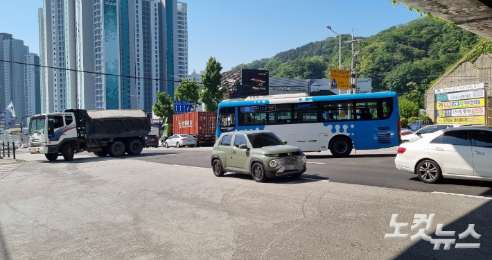 부산 남구 대남초등학교 진입로 앞 통학버스 승하차 지점에서 바라본 도로 모습. 덤프트럭과 시내버스가 진입로 쪽으로 유턴하고 있다. 박진홍 기자