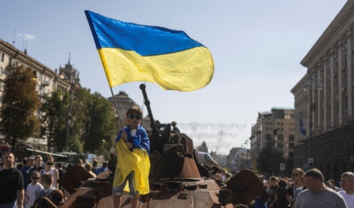 지난 2022년 8월 우크라이나 수도 키이우에 전시된 러시아 탱크 위에 선 한 소년이 우크라이나 국기를 흔들고 있는 모습. 연합뉴스