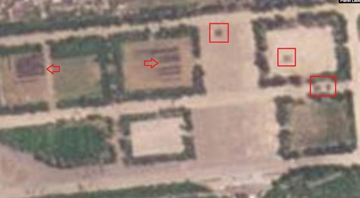 북한 열병식 훈련장을 촬영한 19일 자 위성사진. 훈련장 중심부와 동쪽 공터, 길목 등에 병력 대열(사각형 안)이 보인다. 북서쪽 공터에는 차량 여러 대(화살표)가 주차돼 있다. VOA 홈페이지 캡처