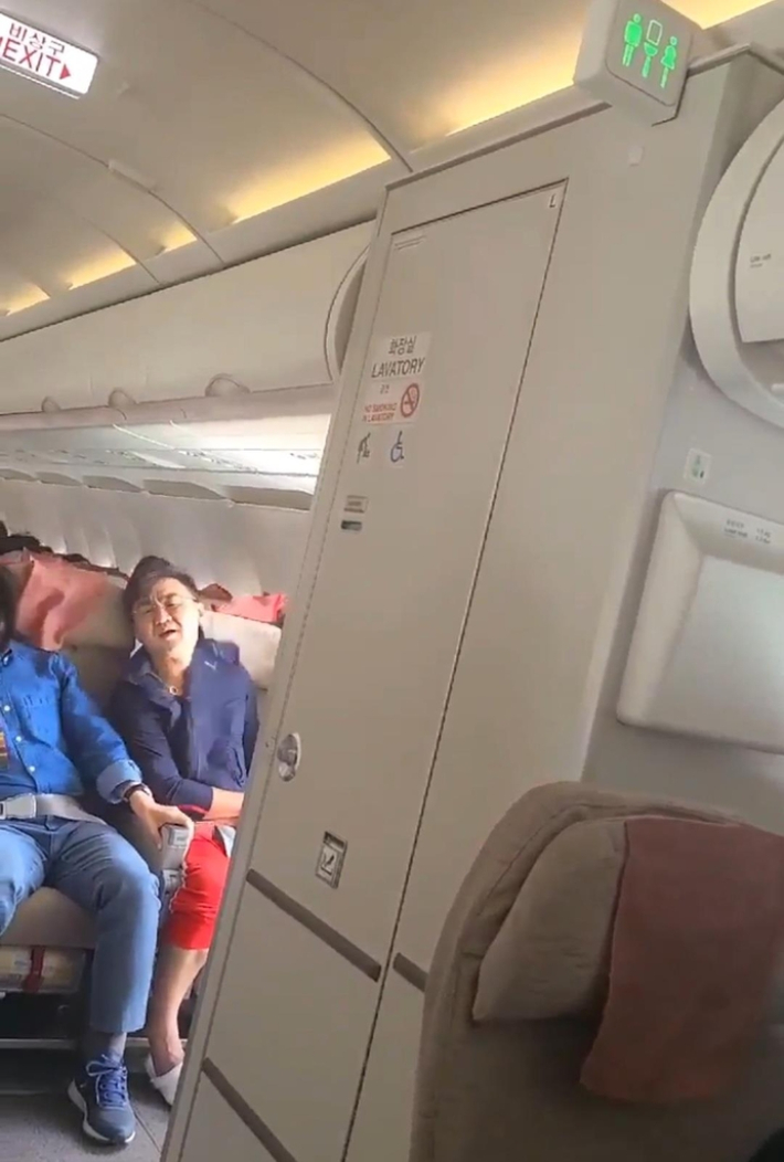 문 열린 채 운항 중인 아시아나 항공기 안에 앉아 있는 이윤준(사진 속 빨간 바지)씨 모습. 연합뉴스