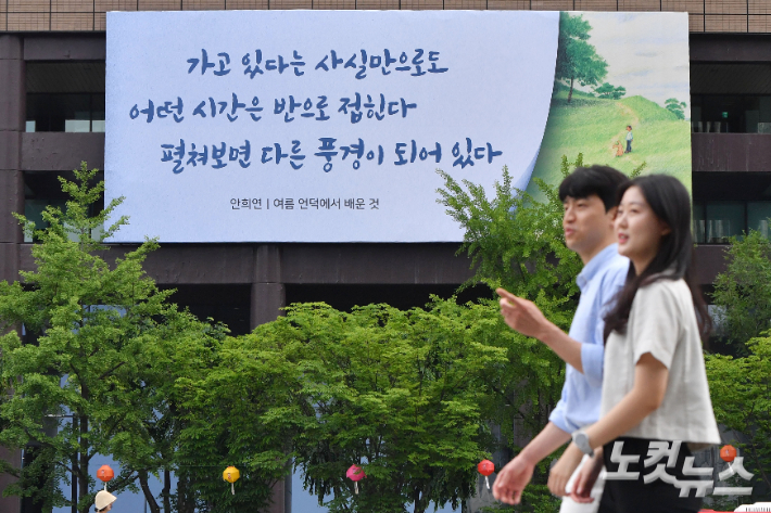 30일 오전 서울 종로구 교보생명 빌딩 외벽에 걸린 광화문글판 앞으로 마스크를 벗은 시민들이 걸어가고 있다. 류영주 기자