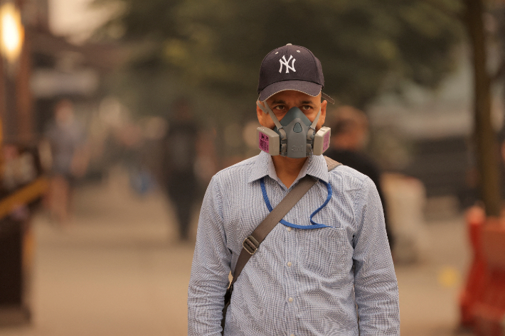 캐나다에서 발생한 산불 연기가 미국의 동부 지역까지 확산하는 가운데 7일(현지시간) 한 남성이 방진 마스크를 쓴 채 뉴욕 거리를 걷고 있다. 연합뉴스