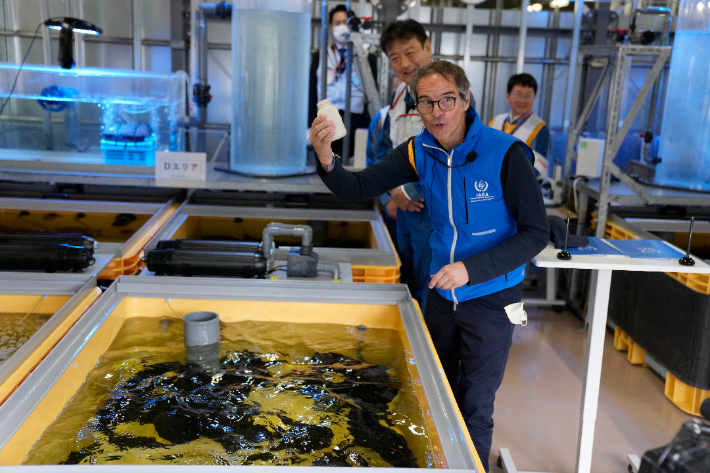 지난 5일 일본 후쿠시마 원자력 발전소를 방문한 라파엘 그로시 IAEA 사무총장이 처리된 오염수를 넙치에게 먹인 뒤 빈병을 들어올리고 있다. 연합뉴스