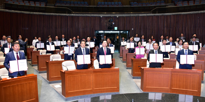 국민의힘 김기현 대표, 윤재옥 원내대표 등 의원들이 지난 6월 21일 서울 여의도 국회에서 열린 의원총회에서 '국회의원 불체포특권 포기 서약서'를 들어보이고 있다. 윤창원 기자