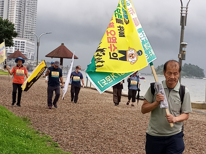 이무성 광주대학교 해직교수가 맨 앞에서 깃발을 든 채 여수 웅천 일대를 걷고 있다. 전동NCC 제공