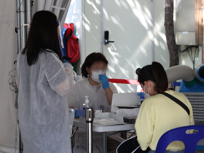 5주 연속 코로나19 확진자 증가세가 이어졌던 지난 2일 오후 서울 한 보건소 선별진료소에서 시민들이 PCR 검사를 받기 위해 문진표를 작성하고 있다. 연합뉴스