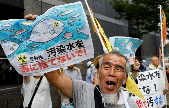 24일(현지시간) 일본 도쿄의 도쿄전력 본사 앞에서 시민들이 "오염수를 바다에 버리지 말라"고 적은 플래카드를 들고 시위하고 있다. 연합뉴스