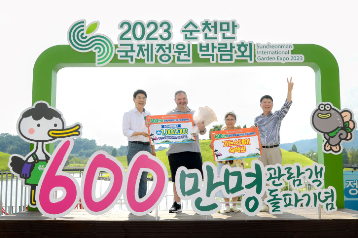 노관규 순천시장(왼쪽)과 순천시의회 정병회 의장(오른쪽)이 27일 순천만국가정원 호수정원 나루터에서 600만번째 관람객인 '폴 안도노브(Paul Andonov)' 부부를 축하하고 있다. 순천시 제공