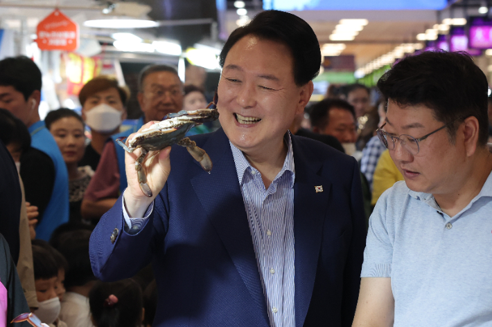 윤석열 대통령이 31일 서울 동작구 노량진수산시장을 찾아 꽃게를 구매하며 상인과 대화하고 있다. 연합뉴스