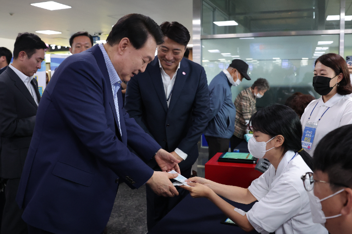 윤석열 대통령이 31일 서울 동작구 노량진수산시장의 '전통시장 온누리 상품권 환급행사장'에서 구매 영수증을 내고 온누리상품권(2만원)을 환급받고 있다. 연합뉴스